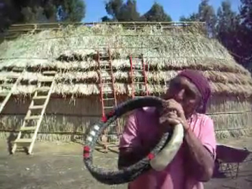 Trutruca in Form eines Horns, gespielt,
                            mit Ruka im Hintergrund