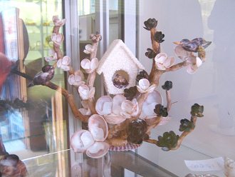 Kunsthandwerk mit Meeresmuscheln, ein Haus
                        im Bltenbaum