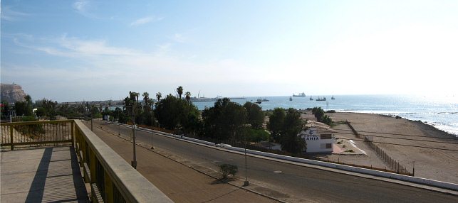 Chile-Allee, Sicht von der Brcke ber
                            die Eisenbahnlinie auf die leere
                            Porcel-Allee, auf den Morroberg, den Hafen
                            von Arica, das Hotel "Zur Bucht"
                            (hotel Baha) und den Chinchorrostrand,
                            Panorama