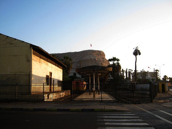 Arica: Die Bahnstation nach Bolivien, der
                        geschlossene Eingang an der Strasse zum 18.
                        September mit dem Morroberg im Hintergrund im
                        Abendlicht