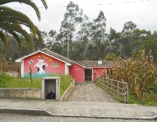 Ein Kindergarten in Peguche mit einer
                          aufgemalten Kuh an der Fassade