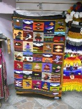 Wandteppich mit kleinen Motiven:
                              M�nner, Frau mit Kind auf dem R�cken,
                              Vulkan, Tiere etc.