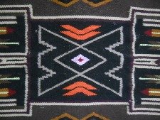 Wandteppich mit grafischem Design mit
                            Pfeilen, Treppen und Romben in der Mitte,
                            das Zentrum mit den Romben