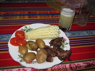 Abendessen mit Fleisch, Kartoffeln,
                          Choclo (gednsteter Maiskolben) und Tomaten
