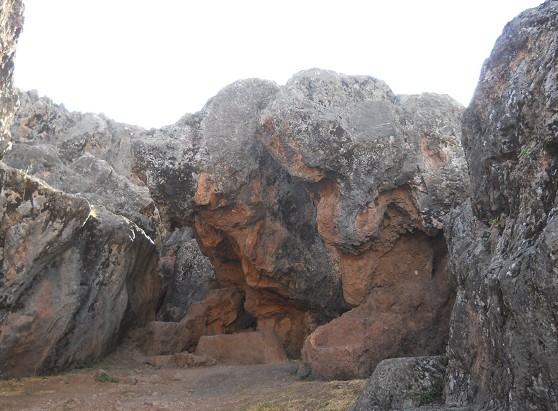 Cusco Sacsayhuamn, zona final de roca negra roja con una cueva con una mesa en piedra central