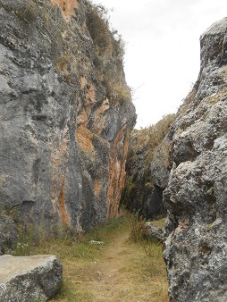 Cusco Sacsayhuamn, Zone X (Laq'o, Laco, Mondtempel), der Weg fhrt an geschnittenen, schwarz-roten Felsen vorbei