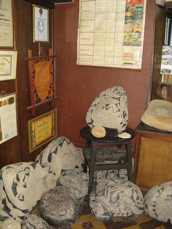La piedra con dinosaurio con sabio con
                            hacha y soles en la oficina del museo