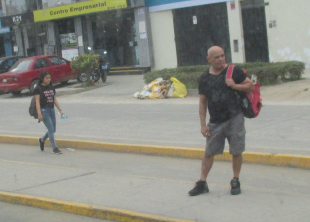 Un calvo joven
              espera a un bus en la avenida Huandoy en Los Olivos,
              primer plano