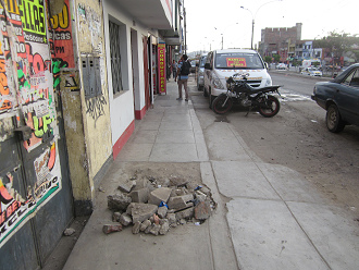Hueco
              gigante en la acera de la avenida Tupac Amru en Comas
              llenado con derrumbe as NADIE puede pasar