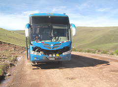 Die Frontseite des Reisebusses und der
                        Feldweg mit seinen Schlaglchern, 8:30 Uhr