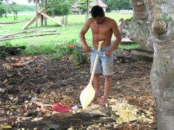 Amazonas-Flussdorf 02, ein Indigena-Mann
                          schnitzt mit seiner Machete ein Paddel