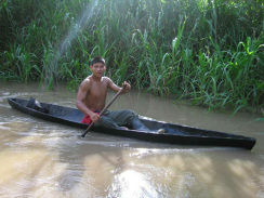 Amazonas-Flusslauf, Seitenarm 06, ein
                          Indigena-Mann in Stiefeln fhrt auf einem
                          braunen Seitenarm Kanu