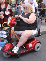 Degenerierte "USA", eine Frau mit
                Giga-�bergewicht auf einem W�gelchen in einem
                Einkaufszentrum "Walmart"